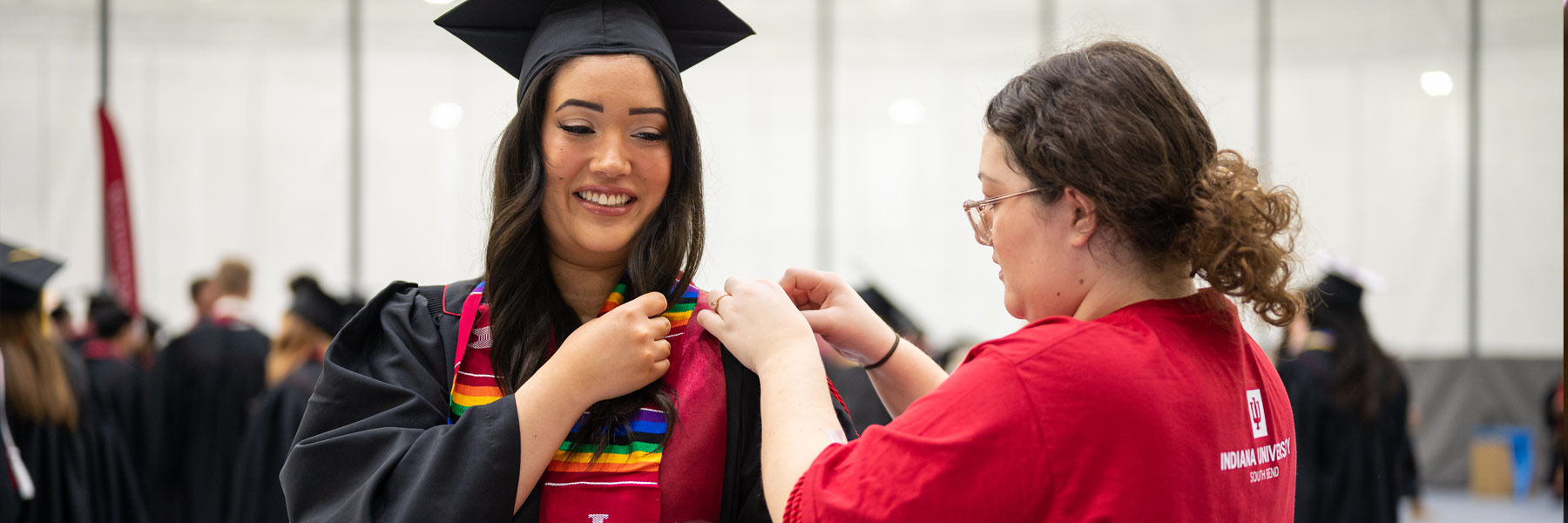 A female graduate gets a little help pinning her honor cords