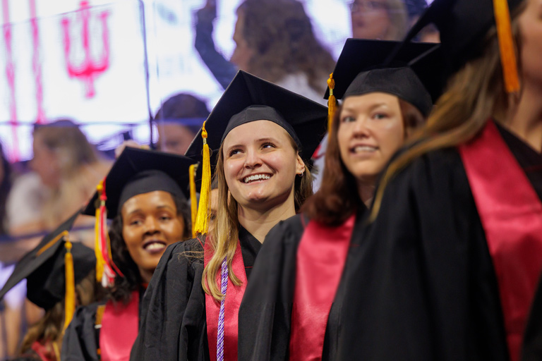 A single graduate in a line of graduates looks optimistically upward